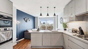 Una cocina moderna con una isla central, horno empotrado y vistas a la ciudad.