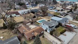 Vista aérea de una zona residencial con casas, una piscina y una playa al fondo.