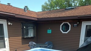 Un jacuzzi en un patio trasero con una casa de madera, una mesita y sillas.