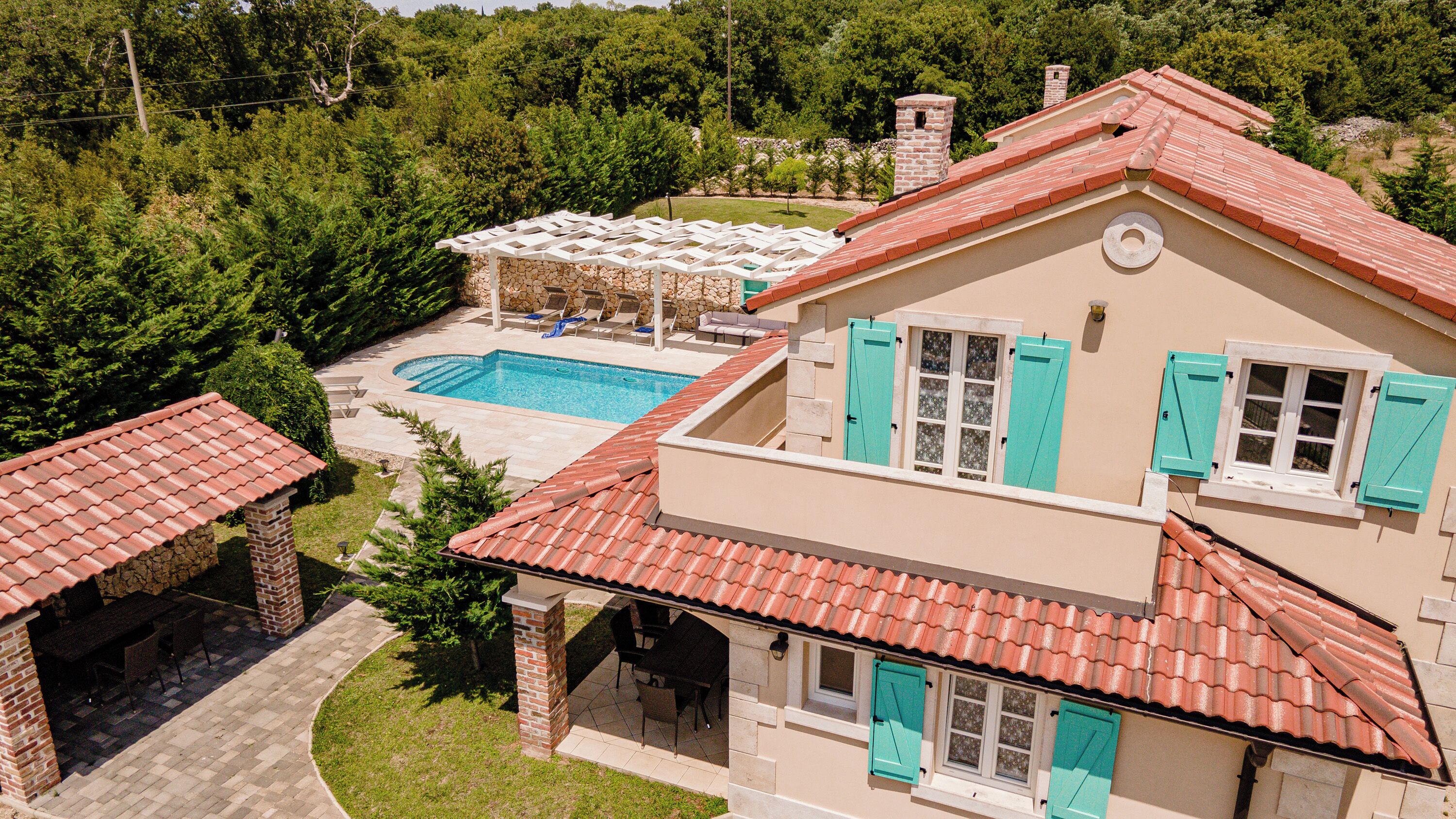 A two-story house with a swimming pool, outdoor seating, and a garden.