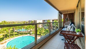 Un balcon donnant sur une piscine et la végétation environnante.