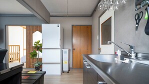 A modern kitchen with a stainless steel sink, a refrigerator, and a wooden door. - VITA (Furano)