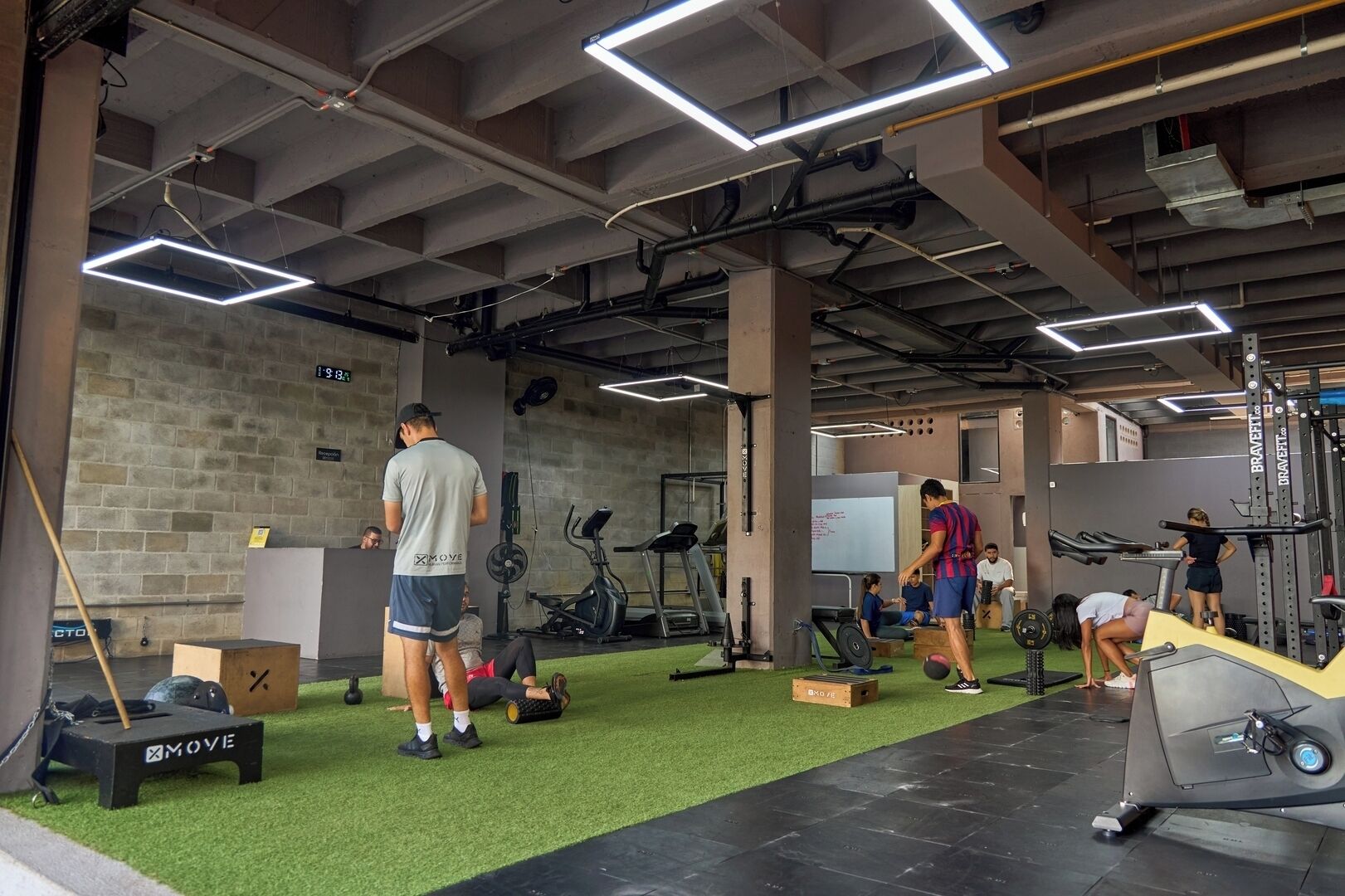 Une salle de sport équipée de matériel d’exercice, dotée d’un revêtement de sol synthétique et d’un mur en briques.