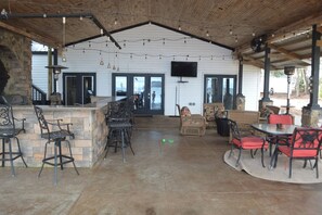 An outdoor patio area with stone walls, metal chairs, and tables. - 5 BR House Lake Retreat w/ Hot Tub, Sleeps 12 (Gilbert)