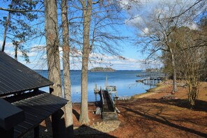 A lakeside cabin with a dock extending into the water, surrounded by trees and a clear sky. - 5 BR House Lake Retreat w/ Hot Tub, Sleeps 12 (Gilbert)