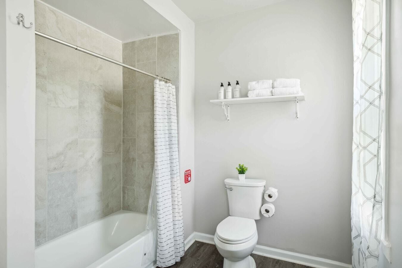 Un baño con ducha, inodoro y un estante con artículos de aseo.
