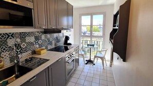 A kitchen with a tiled backsplash, stainless steel appliances, and a small dining area with a table and chairs. - Appt 80m², 13 P,  Disneyland, Fibre, 2 parkings (Chessy)