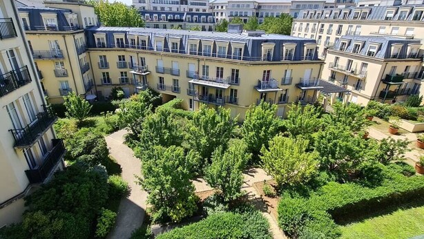 A multi-story residential building with balconies, a central courtyard with trees, and a clear sky. - Appt 80m², 13 P,  Disneyland, Fibre, 2 parkings (Chessy)