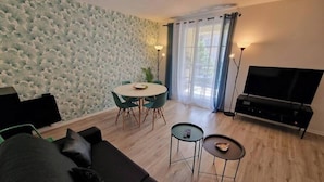 Un salon moderne comprenant un canapé, une table à manger avec des chaises, un téléviseur et une petite table d’appoint.
