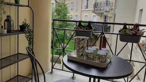 Un balcon avec une balustrade en métal, une petite table et des plantes en pot.
