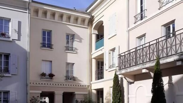 Une cour intérieure avec une pelouse centrale, entourée d’immeubles à plusieurs étages dotés de balcons et de fenêtres.