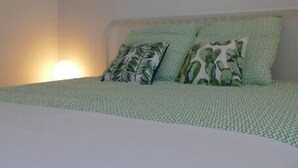 A bedroom with a bed, pillows, and wall-mounted shelves with plants.