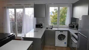 A compact kitchen with a washing machine, a microwave, and a refrigerator.