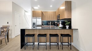 A modern kitchen with a central island, bar stools, and built-in appliances. - Relaxing Nature Escapade with Game Room (Clermont)