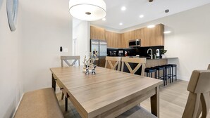 A modern kitchen with wooden cabinets, stainless steel appliances, and a central island with bar stools. - Relaxing Nature Escapade with Game Room (Clermont)