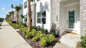 A modern building with a stone facade, a welcoming entrance, and a well-maintained garden with palm trees and shrubs. - Relaxing Nature Escapade with Game Room (Clermont)