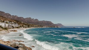 Une vue côtière avec un rivage rocheux, des bâtiments le long de la plage et une montagne en arrière-plan.