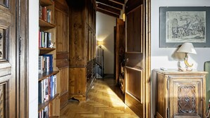 A narrow hallway with wooden bookshelves, a lamp, and a framed picture on the wall.
