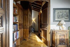 A narrow hallway with wooden bookshelves, a lamp, and a framed picture on the wall.