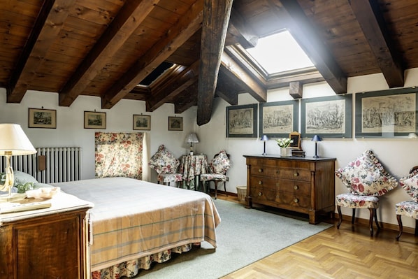 Un dormitorio con techo de madera, una cama, un tocador, un escritorio y un tragaluz.