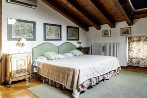 Un dormitorio con una cama, un aparador, un radiador y cuadros en la pared.