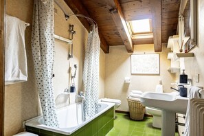 Un baño con bañera, inodoro, lavabo y un espejo grande.