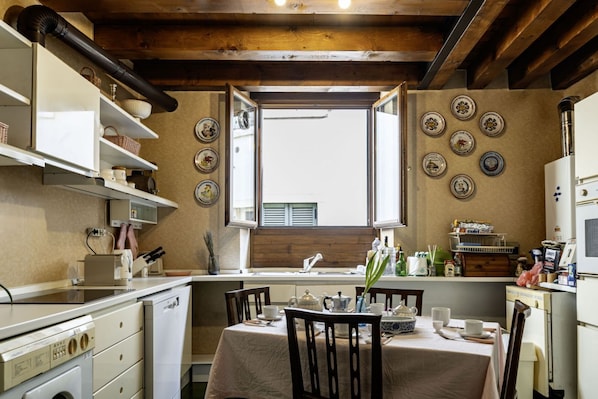 A kitchen with a dining table, chairs, a window, and various kitchen appliances.
