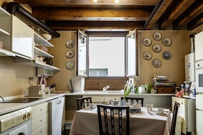 A kitchen with a dining table, chairs, a window, and various kitchen appliances.