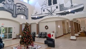 A lobby with a Christmas tree, a large mural, and a reception desk. -  hotel suite with WiFi, fitness room in brilliant Orlando (Orlando)