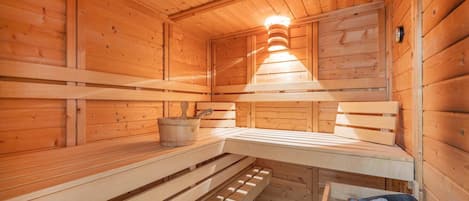 Un sauna avec des bancs en bois, un seau et un récipient rempli de pierres.