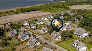An aerial view of a residential area with houses, a body of water, and a heart-shaped icon indicating a location.