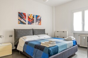 A modern bedroom with a bed, a nightstand, a radiator, and abstract art on the wall.