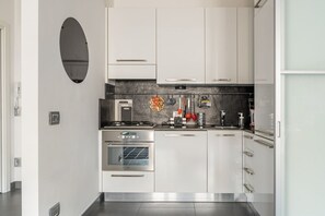 A modern kitchen with white cabinets, a built-in oven, a stove, and a microwave.