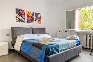 Een moderne hotelkamer met een groot bed, een raam met uitzicht op bomen en abstracte kunst aan de muur.