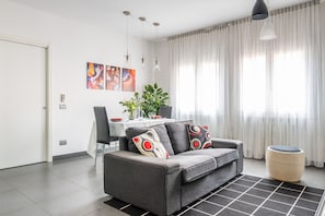 Una sala de estar moderna con un sofá gris, una mesa de comedor y una planta.