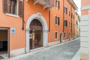 A building with an arched entrance, barred door, and a no parking sign.