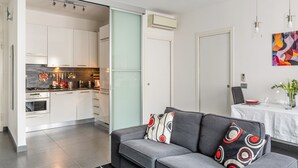 A modern kitchen with white cabinets, a dining area with a table, and a gray sofa with patterned cushions. - GuestHost - Charming apartment of about 50 square meters, perfect for two people, located on the first floor of a building with a lift (NOT suitable for disabled people).The property is located in the heart of the historic center of Verona, a few steps f (Verona)