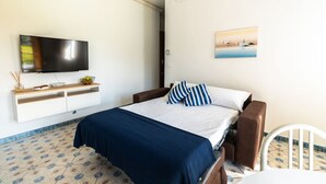Une chambre à coucher avec un lit, une télévision, un tableau et une chaise blanche.