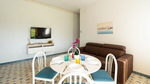 Un espace repas comprenant une table ronde, des chaises, un téléviseur et un canapé.