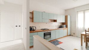 A modern kitchen with light blue cabinets, a wooden countertop, a gas stove, and a microwave. - GuestHost - Gelsomini Apartment Milano (Milano)