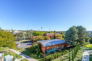 Un edificio de ladrillo con techo verde, rodeado de árboles y un estacionamiento.