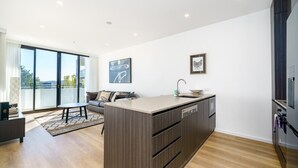Eine moderne Küche mit einer zentralen Kochinsel, einem Essbereich mit Sofa und Tisch sowie großen Fenstern mit Blick.