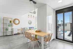 A modern kitchen with a dining area, white cabinetry, and a view of the outdoor pool.