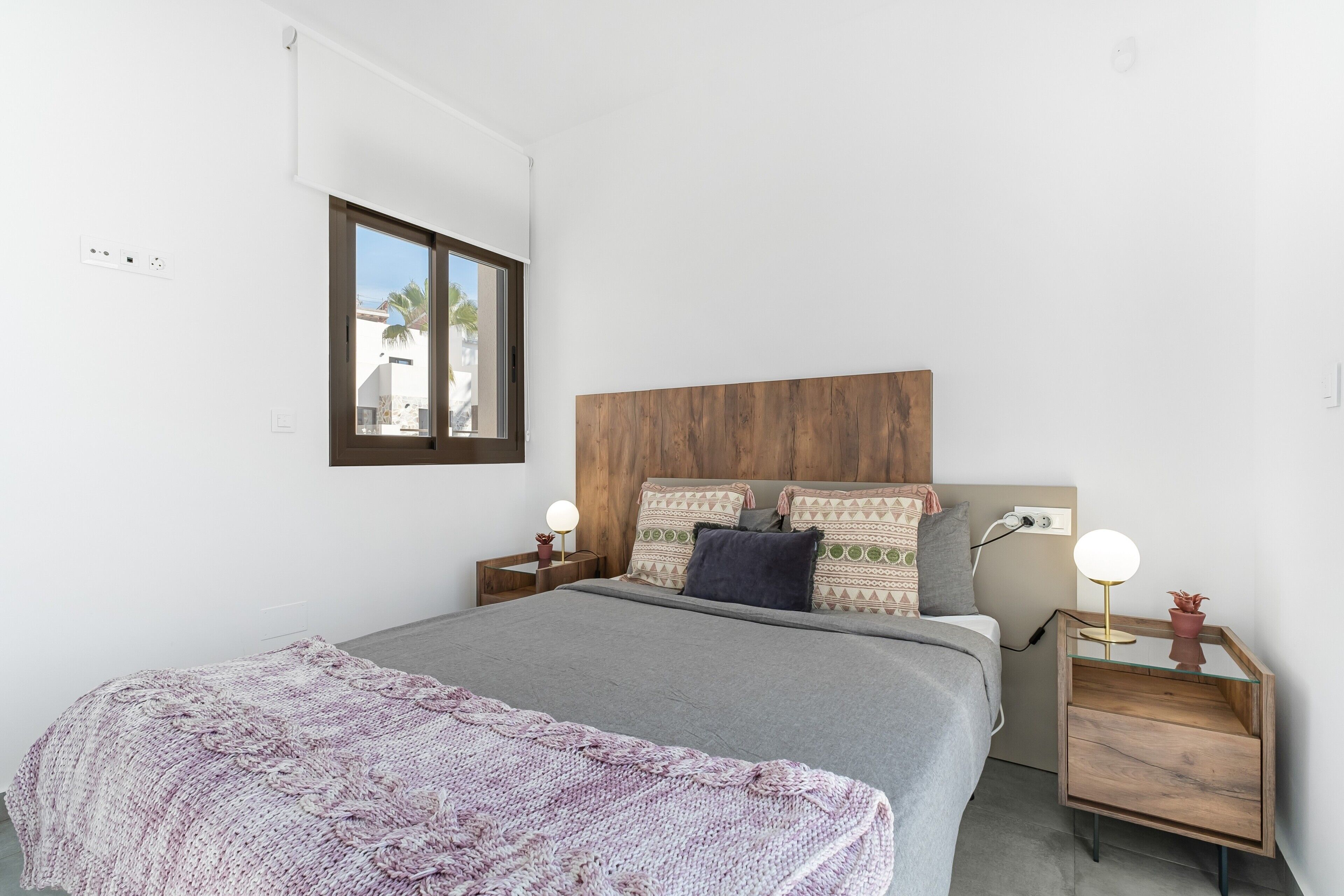 Un dormitorio con una cama, cabecera de madera, mesitas de noche y una ventana.
