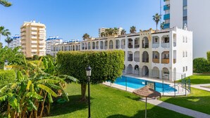 Un hôtel doté d’une piscine, entouré de verdure et de palmiers.