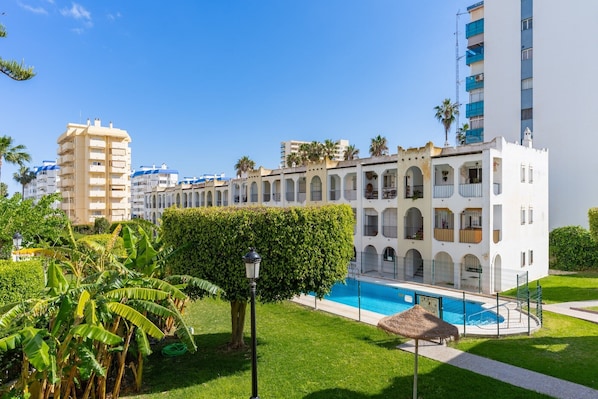 Un hotel con piscina, rodeado de vegetación y palmeras.