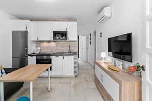 A modern kitchen with white cabinets, a stainless steel refrigerator, a microwave, and a built-in oven.