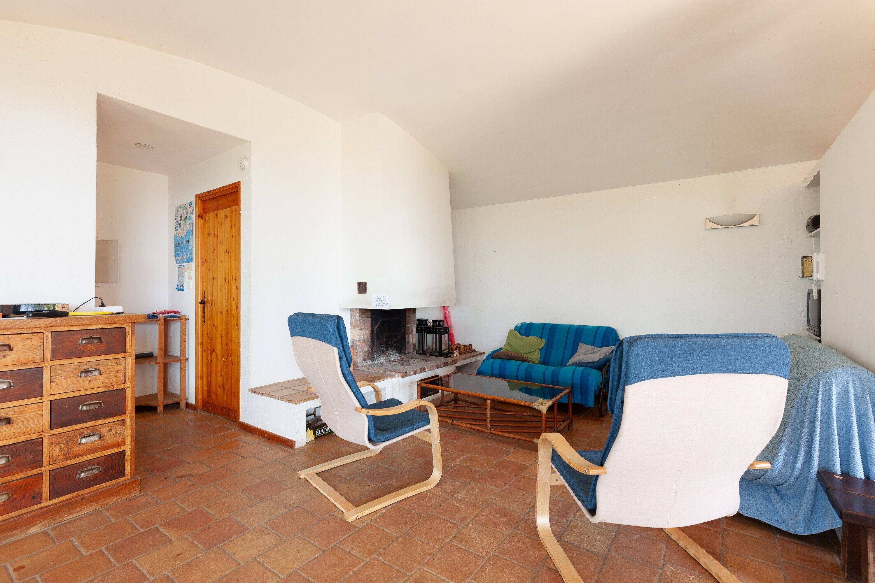 Un salon comprenant un canapé, des fauteuils, une table basse, une cheminée et un meuble en bois.