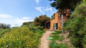 A pathway leading to a building surrounded by greenery and yellow flowers. - Holiday Home 'Catherine Vue Mer Et Terrasse' with Sea View, Private Terrace and Wi-Fi (Carqueiranne)