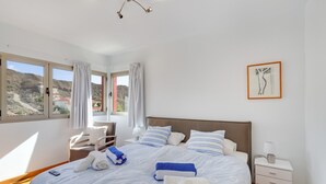 Une chambre d’hôtel avec un lit, une table de chevet, une chaise et une vue sur l’extérieur.